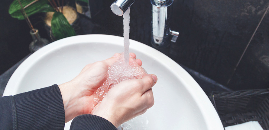 Person som tvättar händerna i rinnande vatten för att tvätta bort bakterier och förkylningsvirus från händerna